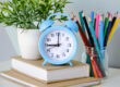 alarm clock on wooden table on blackboard background in classroomback to school concept scaled
