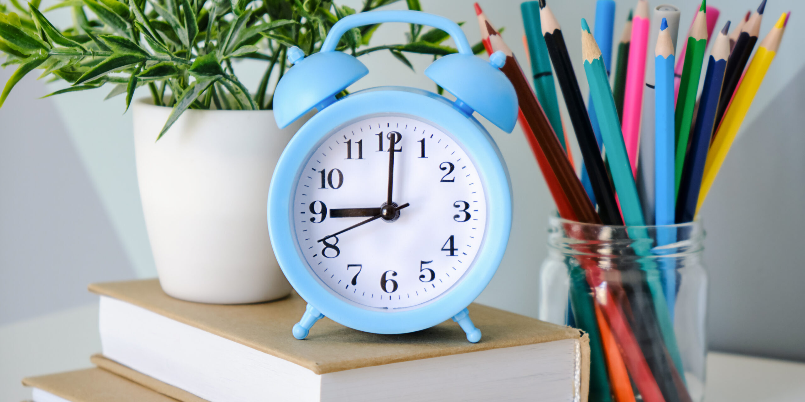 alarm clock on wooden table on blackboard background in classroomback to school concept scaled