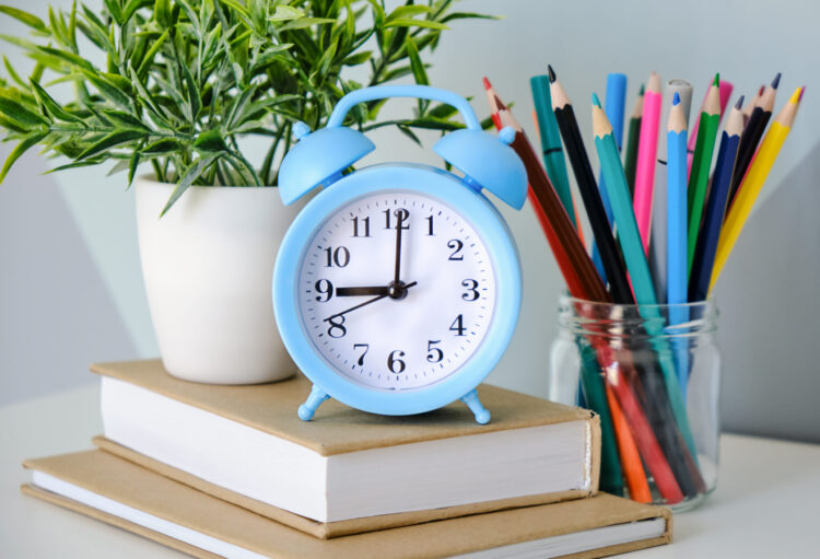 alarm clock on wooden table on blackboard background in classroomback to school concept scaled